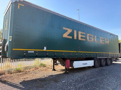 un gros semi-remorque vert garé sur le bord de la route