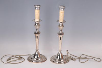 pair of silver plated candlesticks with candles on each of them
