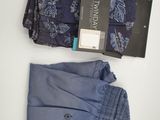 deux paires de pantalons de costume pour homme et une cravate posés sur une surface blanche