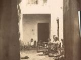 une photo en noir et blanc d'un homme assis dans une cour