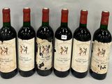six bouteilles de vin rouge sont alignées sur une surface blanche