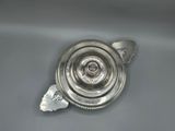 an antique silver plate with a snail on it on a gray surface