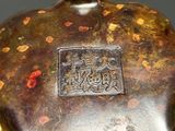 a bronze vase with writing on it sitting on a table