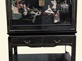 a black cabinet with a painting on it and a shelf underneath it