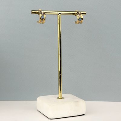 pair of gold plated earrings on a marble stand