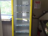 yellow and blue vending machine sitting in a kitchen next to a window