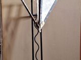 une lampe en métal posée sur un pied au sol