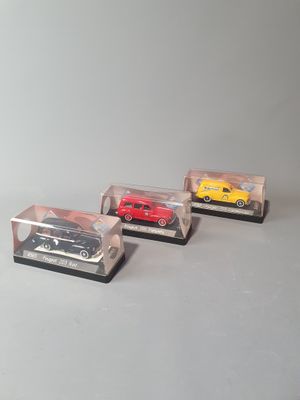 three toy cars are in a clear display case on a gray surface