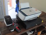une imprimante posée sur une table, à côté d'autres appareils électroniques