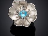 un gros plan sur une bague en forme de fleur sertie d'une topaze bleue