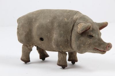 un petit jouet en bois représentant un cochon posé sur une surface blanche