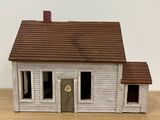 a small white house with a brown roof on a wooden table
