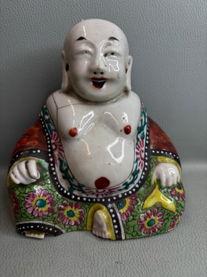 une petite statue représentant un Bouddha souriant, posée sur une table