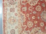 a red and beige rug on display in a glass case