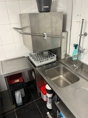 a kitchen with a sink, stove, and trash can in it