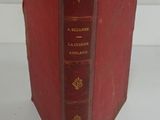 an old red book sitting on top of a table next to a white wall