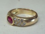 une image d'une bague en or avec une pierre rouge