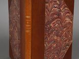 an old book with a brown cover sitting on top of a table