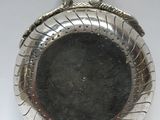 une assiette en argent sur laquelle est représenté un serpent, sur un fond blanc