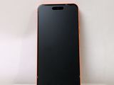 the back of a black and orange cell phone sitting on top of a white shelf