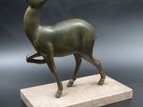 bronze sculpture of a deer on a marble base on a black background