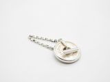 a silver coin with a chain attached to it on a white surface
