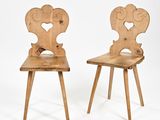 une paire de chaises en bois ornées de cœurs sculptés sur fond blanc