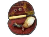 a small red case with a pipe and a wooden stick in it