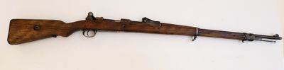 un vieux fusil en bois accroché au mur, à côté d'un mur blanc