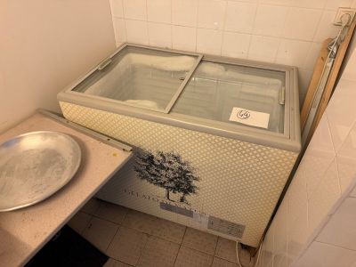 a small freezer in the corner of a bathroom next to a sink