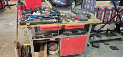 un établi sur lequel sont posés des outils, avec une voiture en arrière-plan
