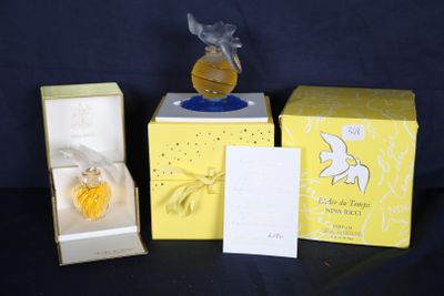 trois flacons de parfum dans leurs boîtes, posés sur une table avec un fond noir
