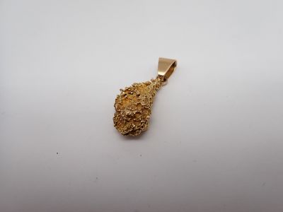 un pendentif en or sur lequel est fixé un petit morceau d'or