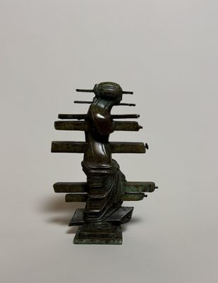 statue en bronze représentant une femme tenant un livre, sur fond blanc