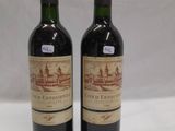 two bottles of red wine sitting on top of a white table