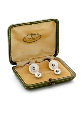 deux paires de boutons de manchette dans un étui, sur fond blanc
