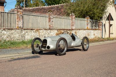 a silver race car that is parked on the side of the road
