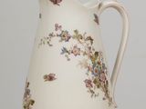 a white pitcher with butterflies on it sitting on a table