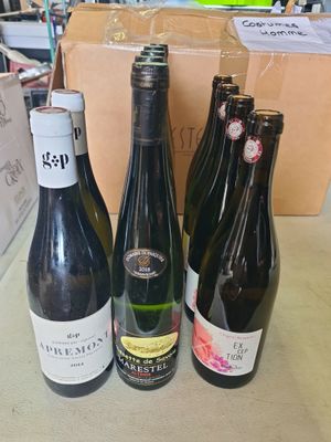 Plusieurs bouteilles de vin sont posées sur une table devant un carton.