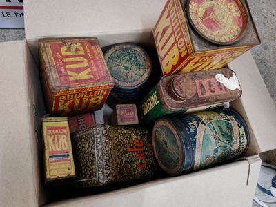 une boîte remplie de boîtes de conserve de toutes sortes, posée par terre