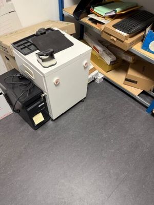 un ordinateur et une imprimante posés sur un bureau dans un coin de la pièce