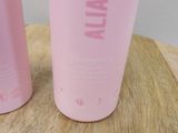 two bottles of pink sham sitting on a wooden table