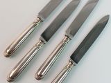 four knives are lined up on a white surface with a silver handle