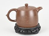 a brown teapot sitting on top of a black stand