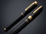 a pair of black and gold fountain pens on a black background
