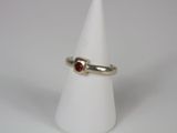 a close up of a ring with a red stone on a white cone