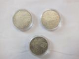 three different coins in plastic containers sitting on a white surface