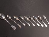 six silver spoons are arranged in a row on a black surface