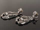 two pairs of diamond earrings on a black surface