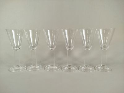 six empty wine glasses lined up in a row on a white surface